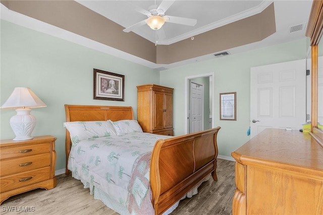 bedroom featuring a raised ceiling, baseboards, visible vents, and light wood-type flooring