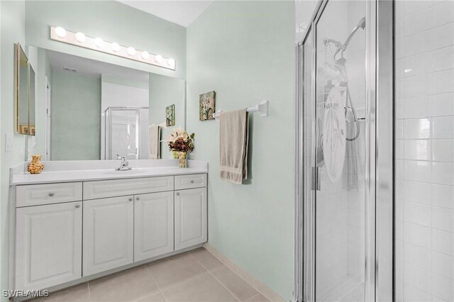 full bath with baseboards, vanity, a shower stall, and tile patterned flooring