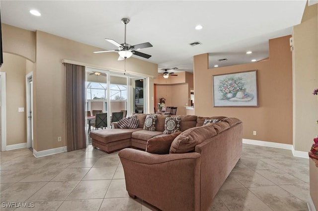 living room featuring arched walkways, light tile patterned floors, visible vents, and a ceiling fan