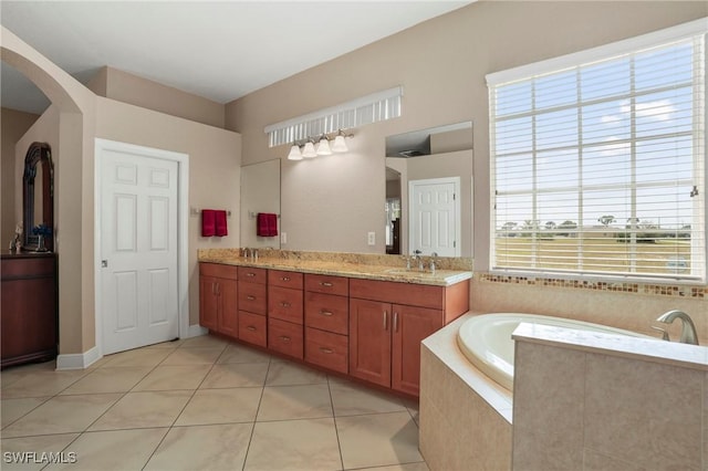 bathroom with double vanity, a garden tub, tile patterned floors, and a sink