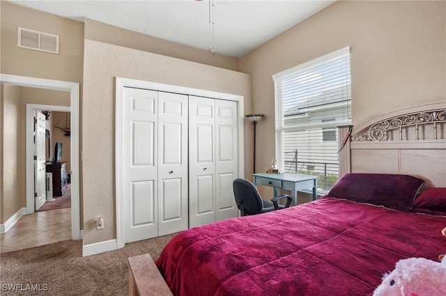 tiled bedroom featuring a closet, visible vents, carpet flooring, and baseboards