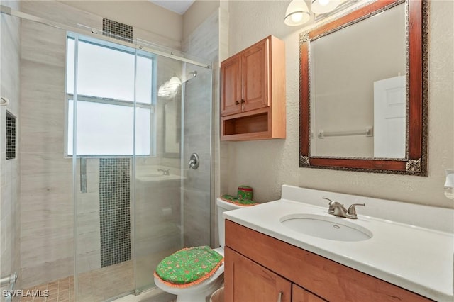 bathroom featuring vanity, a shower stall, toilet, and a textured wall