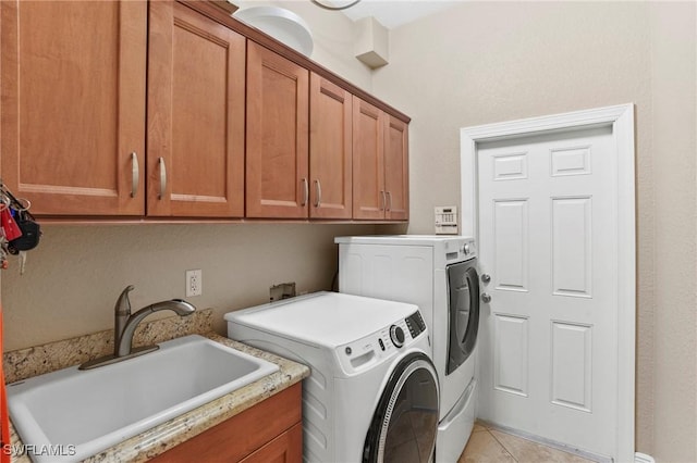 laundry area featuring washing machine and dryer, light tile patterned floors, cabinet space, and a sink