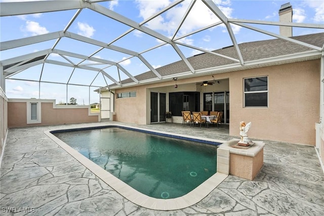 outdoor pool with a patio area, glass enclosure, and ceiling fan