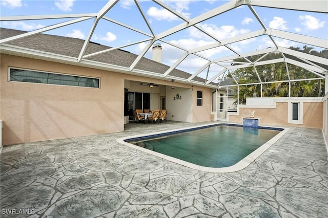 outdoor pool featuring glass enclosure and a patio