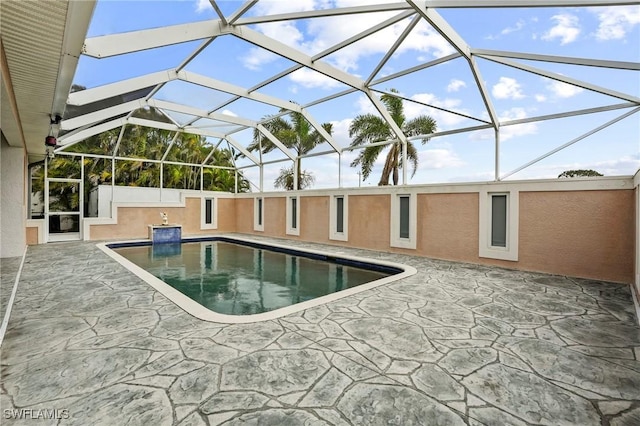 outdoor pool featuring glass enclosure and a patio