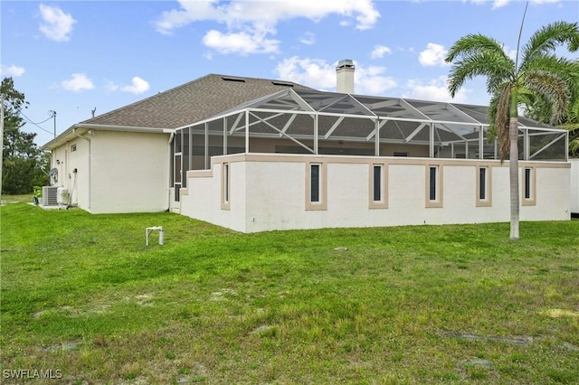 back of house featuring stucco siding, a yard, a chimney, and glass enclosure