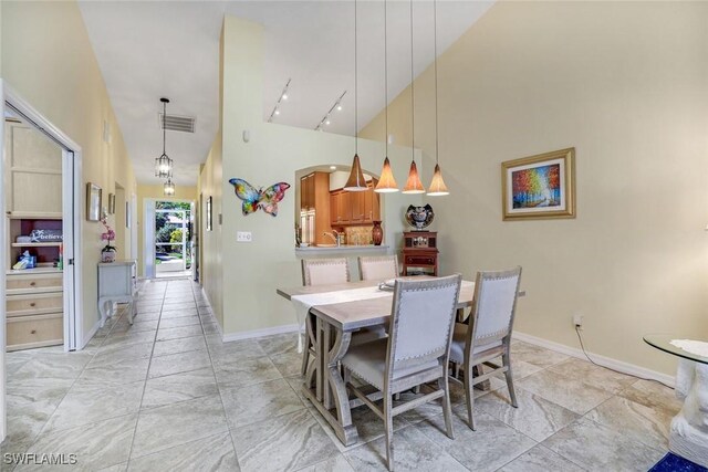 dining room featuring high vaulted ceiling, track lighting, visible vents, and baseboards