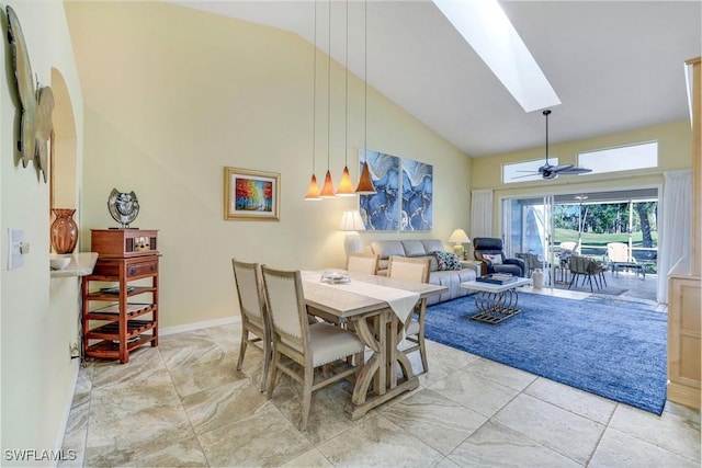 dining room featuring high vaulted ceiling, a skylight, ceiling fan, and baseboards