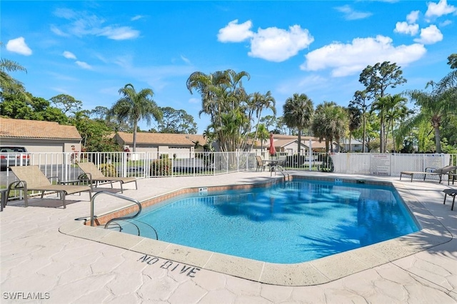community pool featuring fence, a patio, and a residential view