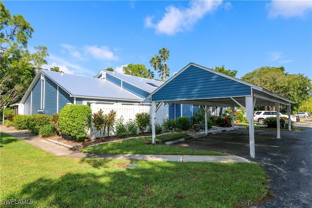 exterior space with metal roof, a carport, a front yard, and fence