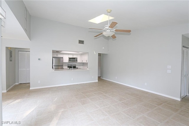 unfurnished living room featuring high vaulted ceiling, a skylight, visible vents, baseboards, and a ceiling fan