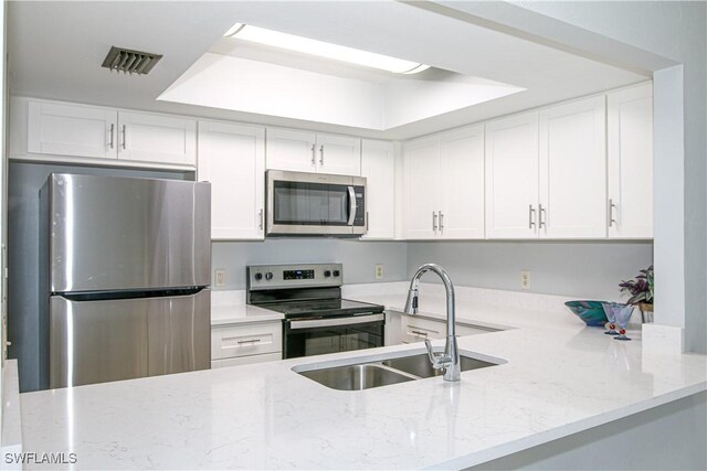 kitchen featuring light stone counters, stainless steel appliances, a sink, visible vents, and white cabinetry