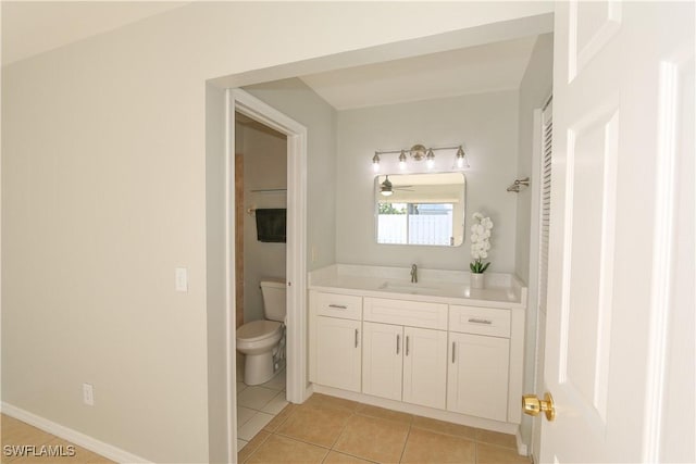 bathroom with toilet, vanity, baseboards, and tile patterned floors