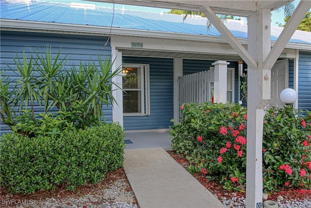 view of exterior entry with a porch and metal roof