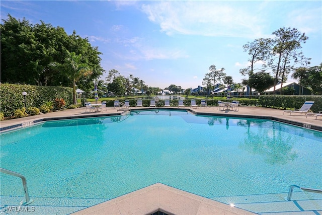 community pool with a patio area and fence