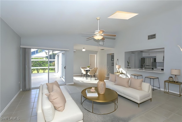 living area with visible vents, baseboards, light tile patterned flooring, high vaulted ceiling, and a ceiling fan