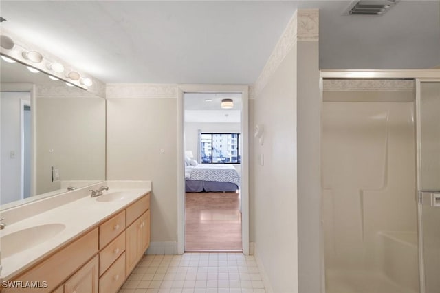 bathroom with ensuite bathroom, a stall shower, a sink, and tile patterned floors