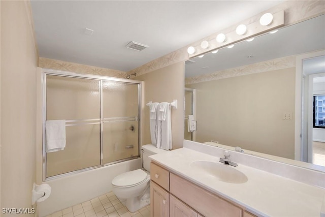 bathroom featuring toilet, shower / bath combination with glass door, visible vents, vanity, and tile patterned floors