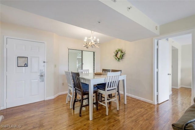 dining space with a notable chandelier, baseboards, and wood finished floors