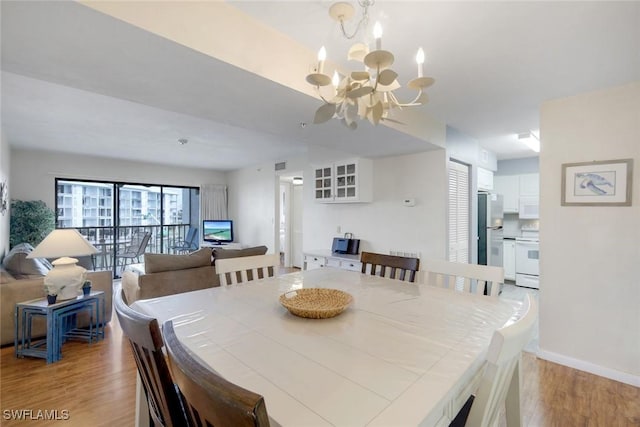 dining space with baseboards, light wood finished floors, visible vents, and an inviting chandelier