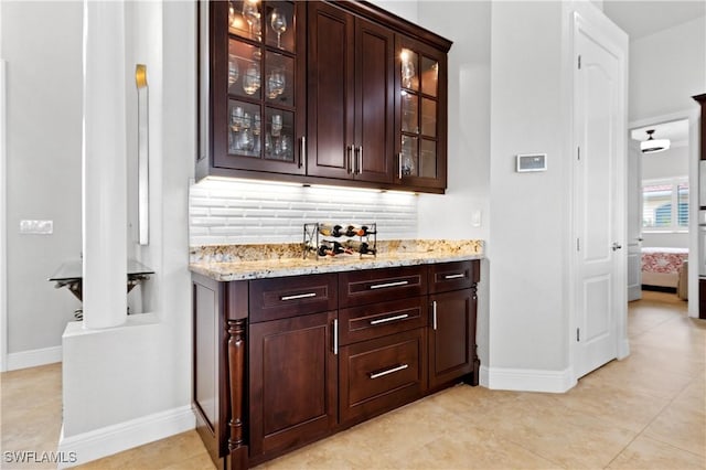 bar with light tile patterned floors, tasteful backsplash, and baseboards