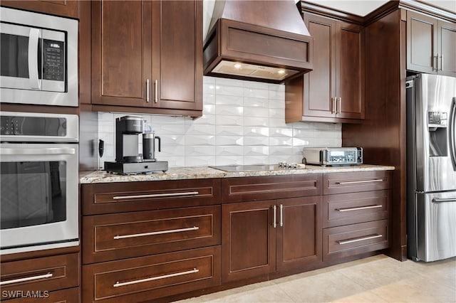 kitchen featuring light stone counters, light tile patterned flooring, appliances with stainless steel finishes, backsplash, and custom exhaust hood