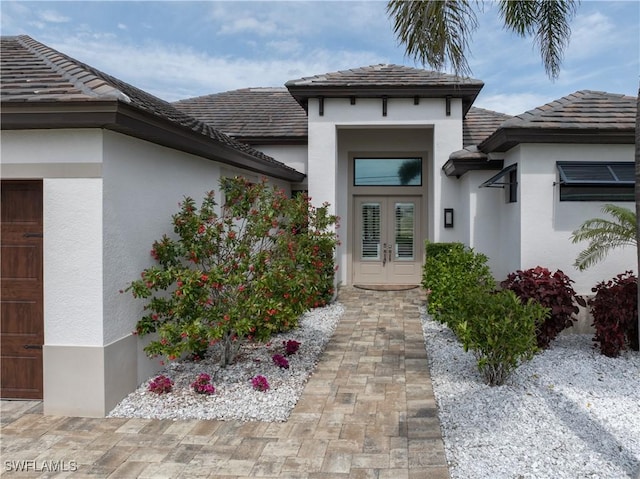 property entrance with french doors, a tiled roof, and stucco siding