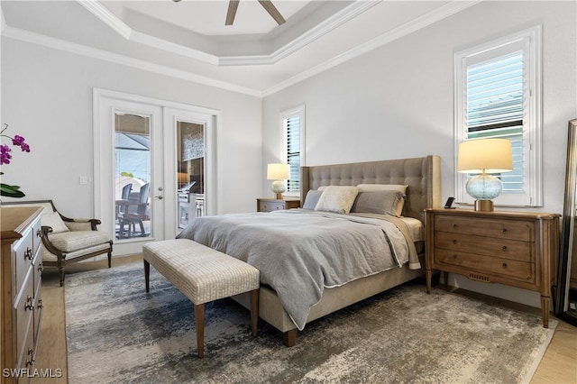 bedroom with a raised ceiling, wood finished floors, access to exterior, crown molding, and french doors