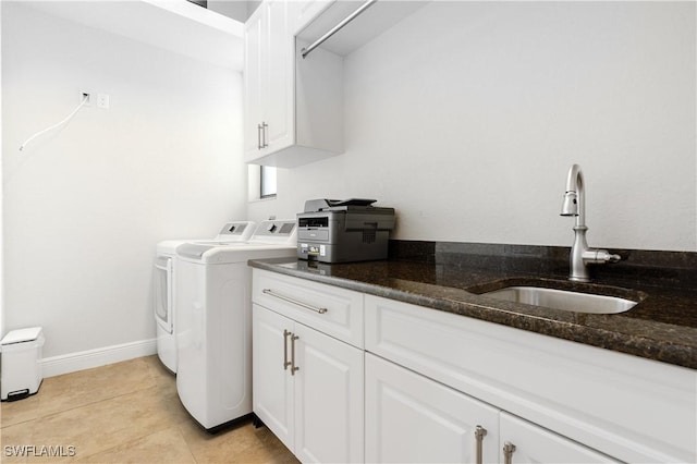 washroom featuring light tile patterned flooring, a sink, baseboards, independent washer and dryer, and cabinet space