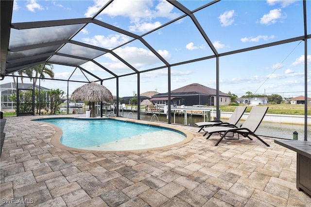 outdoor pool featuring a water view, glass enclosure, and a patio