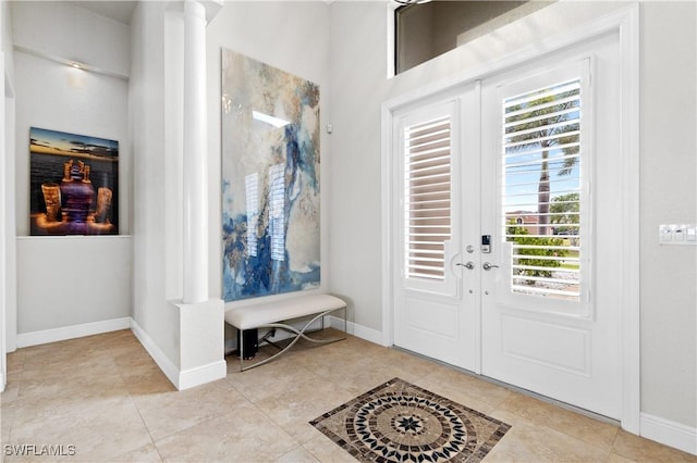 entrance foyer featuring french doors, decorative columns, baseboards, and light tile patterned floors