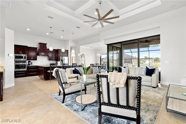 living area with ceiling fan with notable chandelier, coffered ceiling, a towering ceiling, visible vents, and crown molding