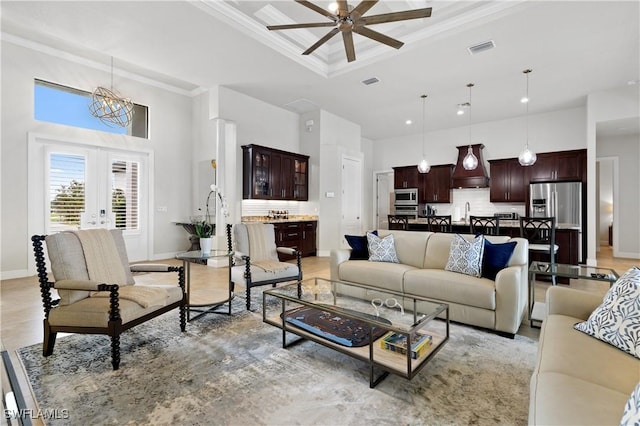 living room with a towering ceiling, baseboards, visible vents, french doors, and crown molding