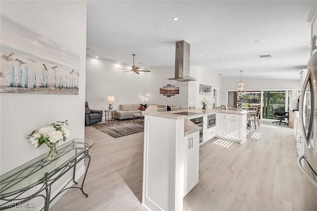 kitchen featuring island range hood, white cabinets, open floor plan, light countertops, and light wood-type flooring