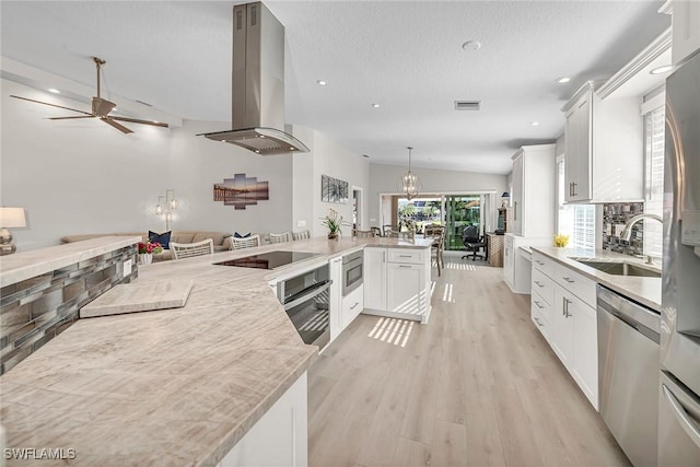 kitchen with island exhaust hood, visible vents, appliances with stainless steel finishes, open floor plan, and white cabinetry