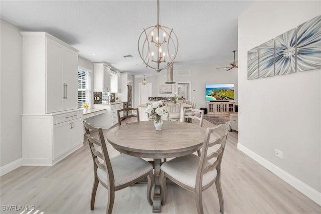 dining room with baseboards, ceiling fan with notable chandelier, visible vents, and light wood-style floors