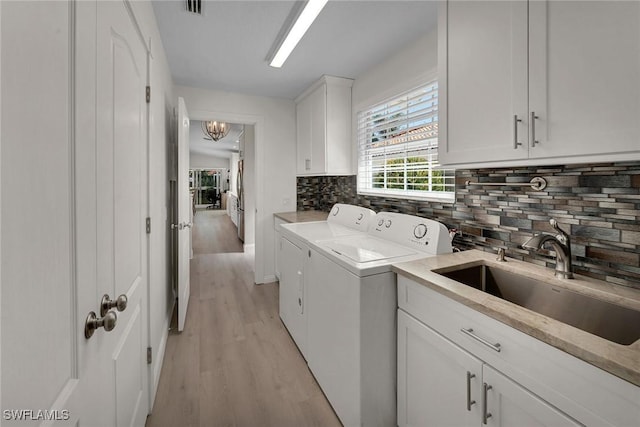 laundry area featuring cabinet space, visible vents, light wood-type flooring, washing machine and dryer, and a sink