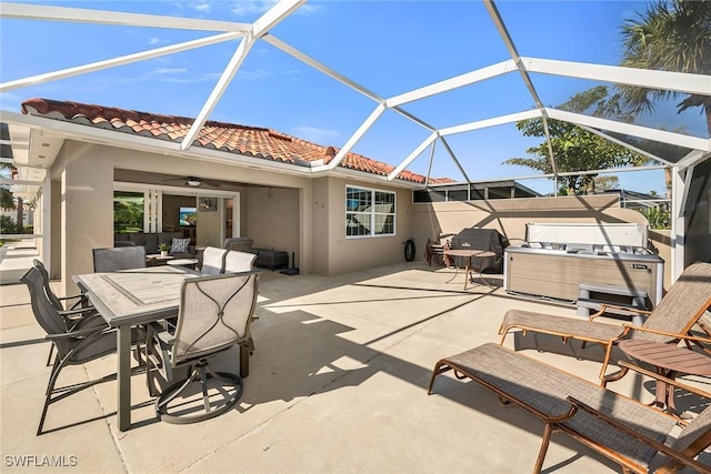 view of patio / terrace with a lanai, a hot tub, ceiling fan, and outdoor dining space