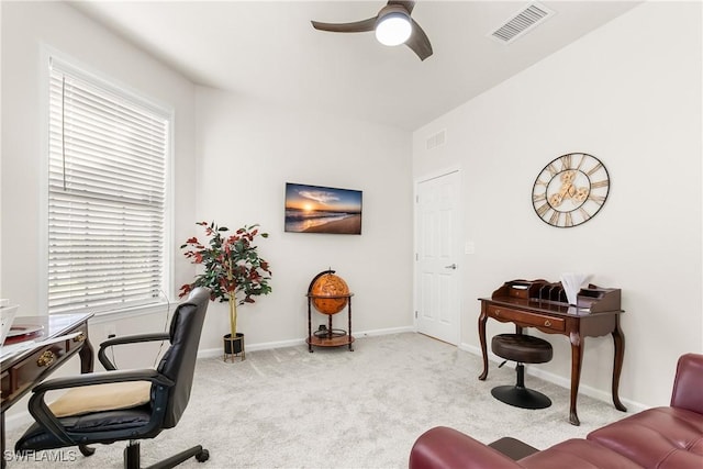 carpeted office space featuring baseboards, visible vents, and a ceiling fan
