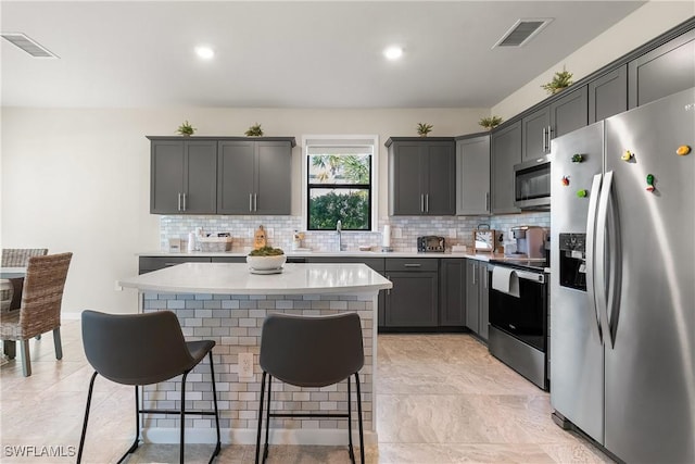 kitchen featuring stainless steel appliances, a breakfast bar, a sink, and visible vents