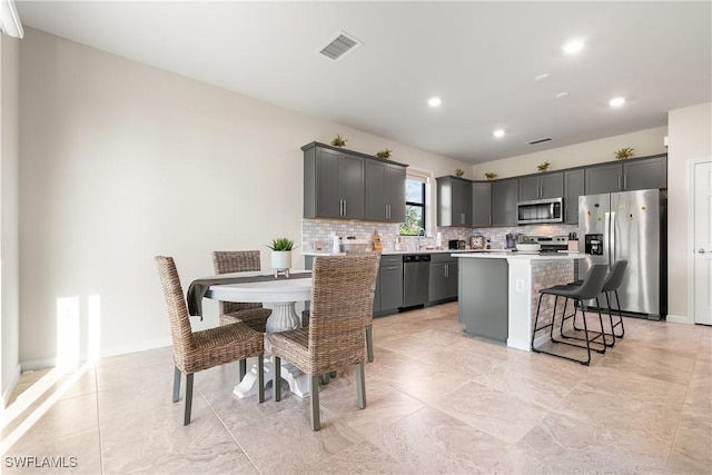 kitchen with light countertops, appliances with stainless steel finishes, backsplash, and visible vents