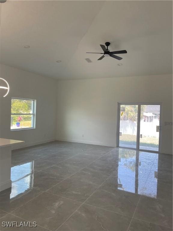 spare room with visible vents, a ceiling fan, and baseboards