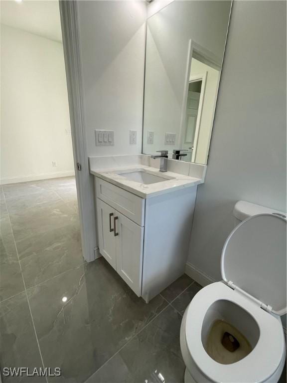 half bathroom with toilet, vanity, and baseboards