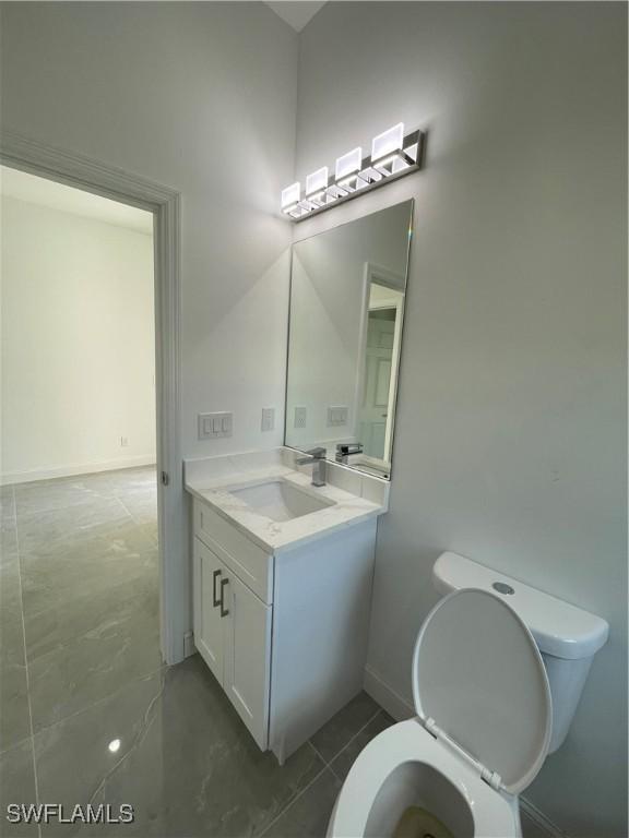 bathroom featuring baseboards, toilet, and vanity