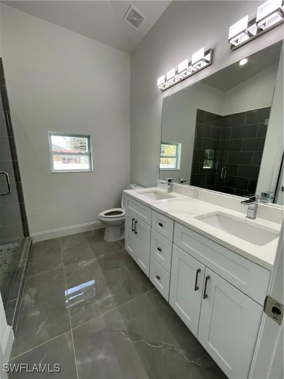 bathroom featuring a sink, marble finish floor, a stall shower, and double vanity