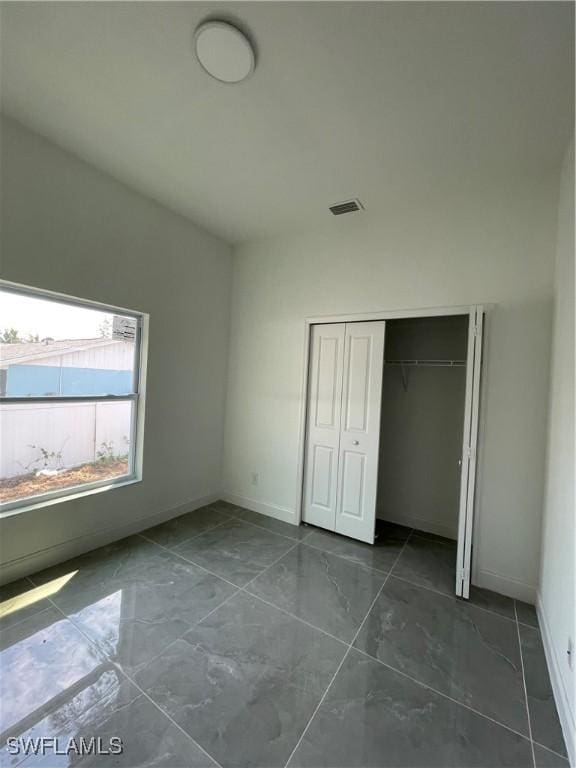 unfurnished bedroom featuring visible vents, baseboards, and a closet