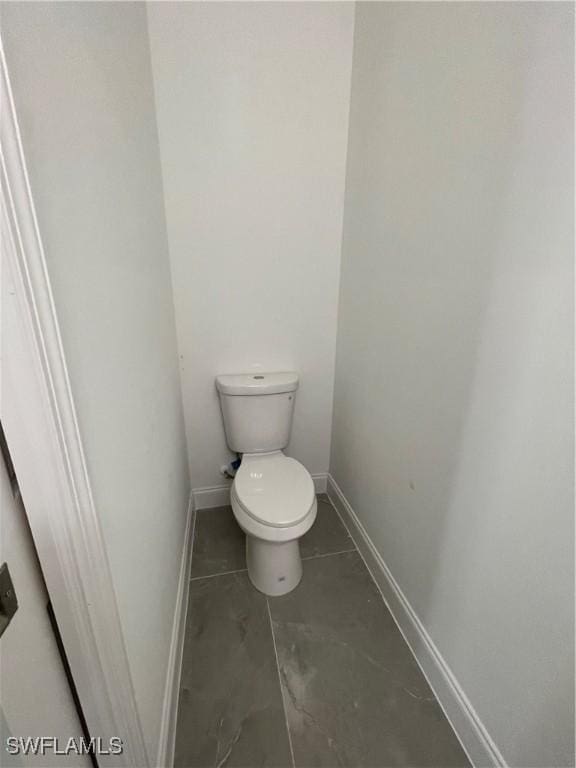 bathroom with toilet and baseboards