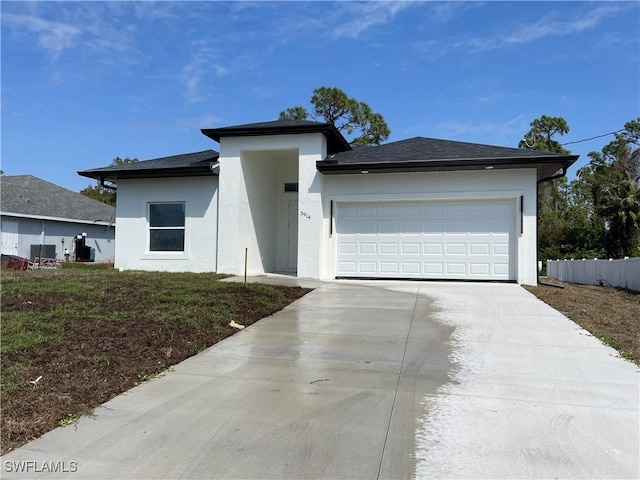 prairie-style home featuring a front yard, fence, driveway, stucco siding, and a garage