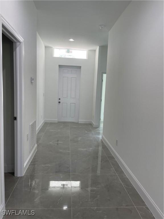 corridor with visible vents, marble finish floor, and baseboards